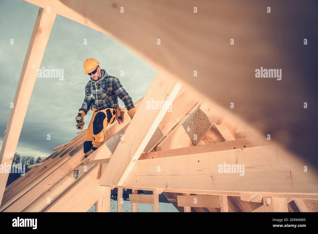 Caucasica Casa di legno Skeleton telaio lavoratore in costruzione nei suoi 40 sul nuovo telaio del tetto. Nuovo tema di sviluppo domestico. Foto Stock