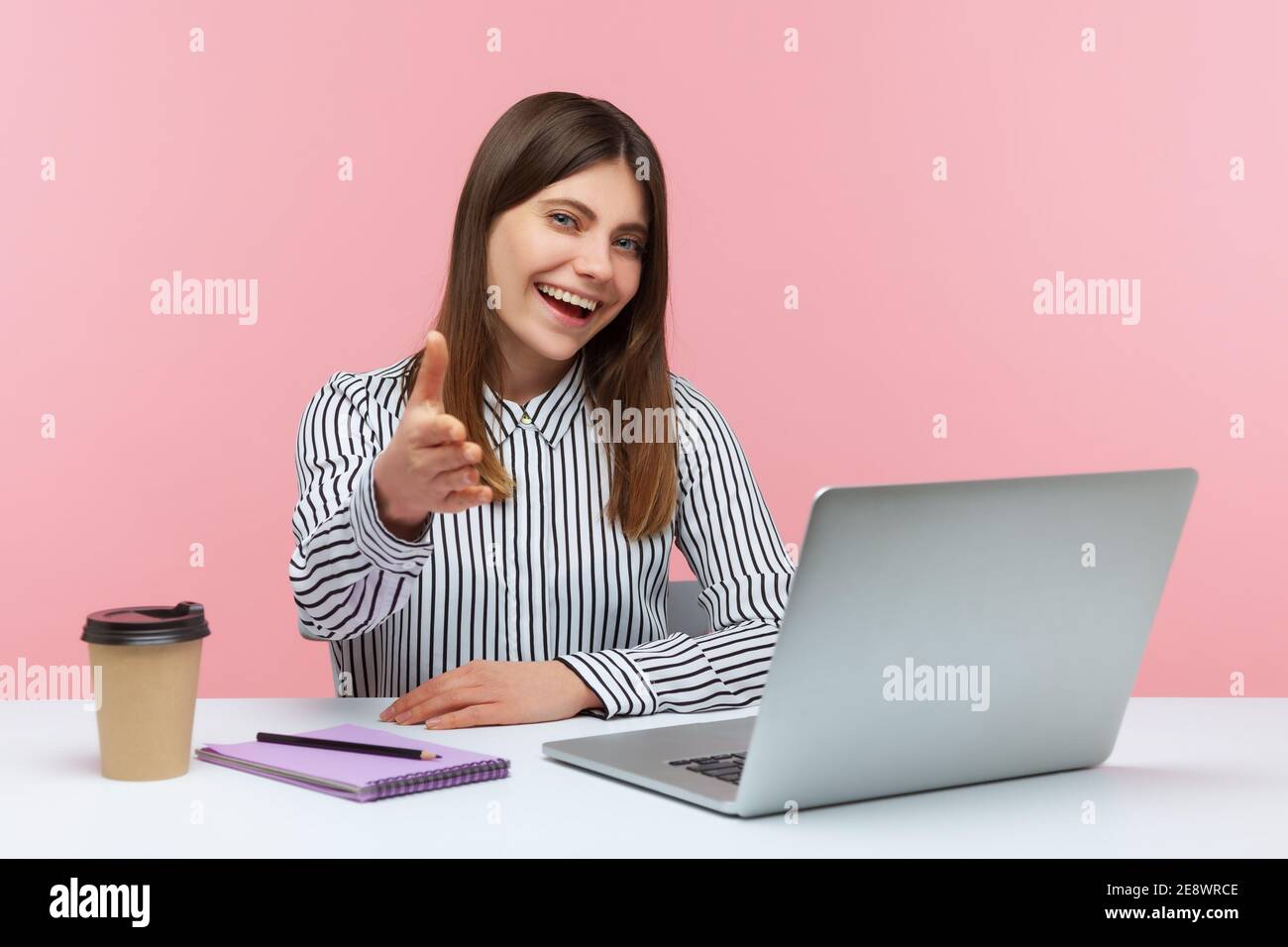 Donna d'affari positiva in camicia a righe che tiene la mano per la stretta di mano seduto sul posto di lavoro, accogliendo i partner, mantenendo la riunione di affari. Monolocale interno Foto Stock