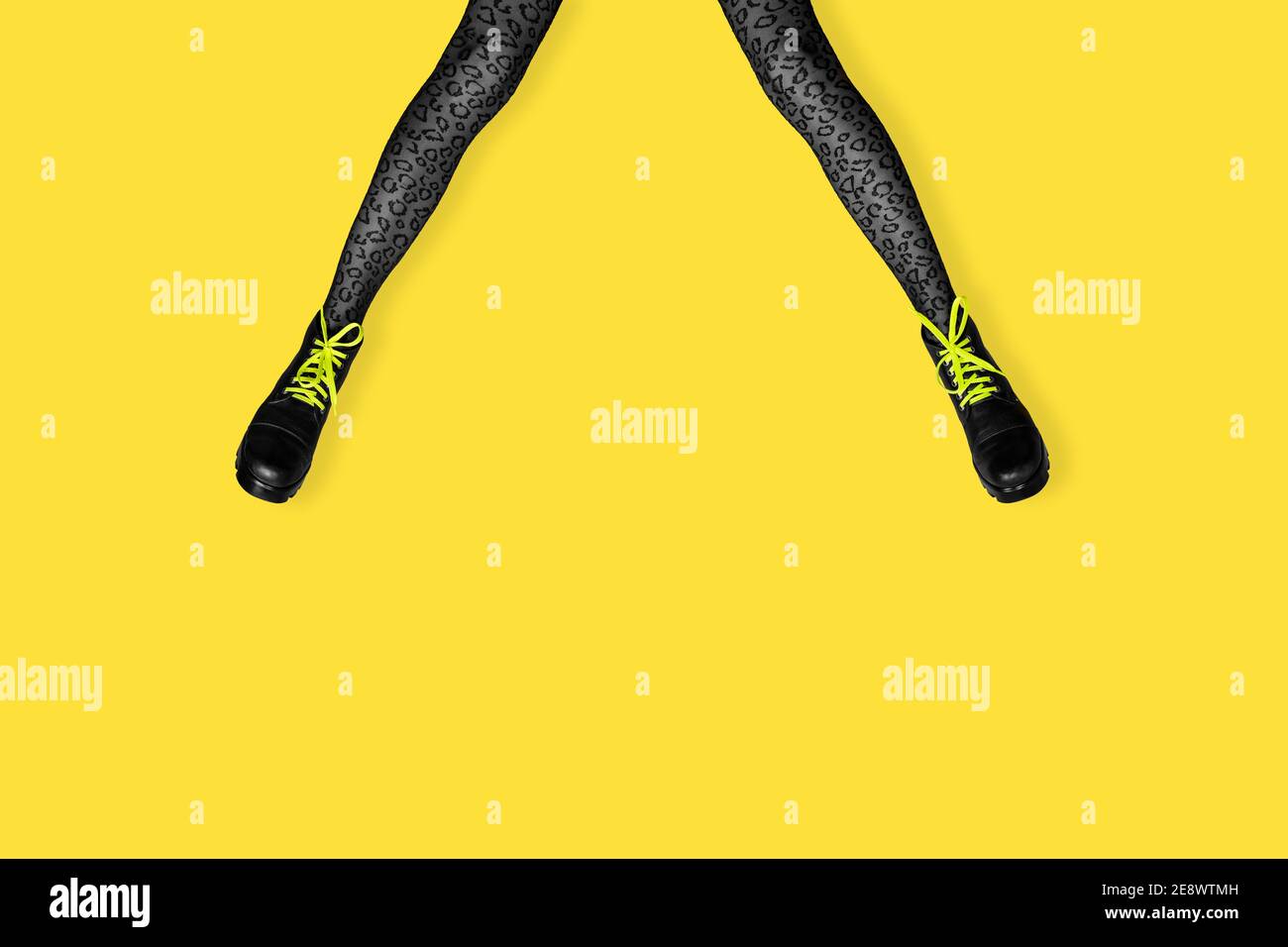Nuovi stivali grigi femminili con lacci giallo brillante su lunghe gambe snella donna in tiger grigio stampa collant isolato su sfondo giallo. Concetto di arte pop ba Foto Stock