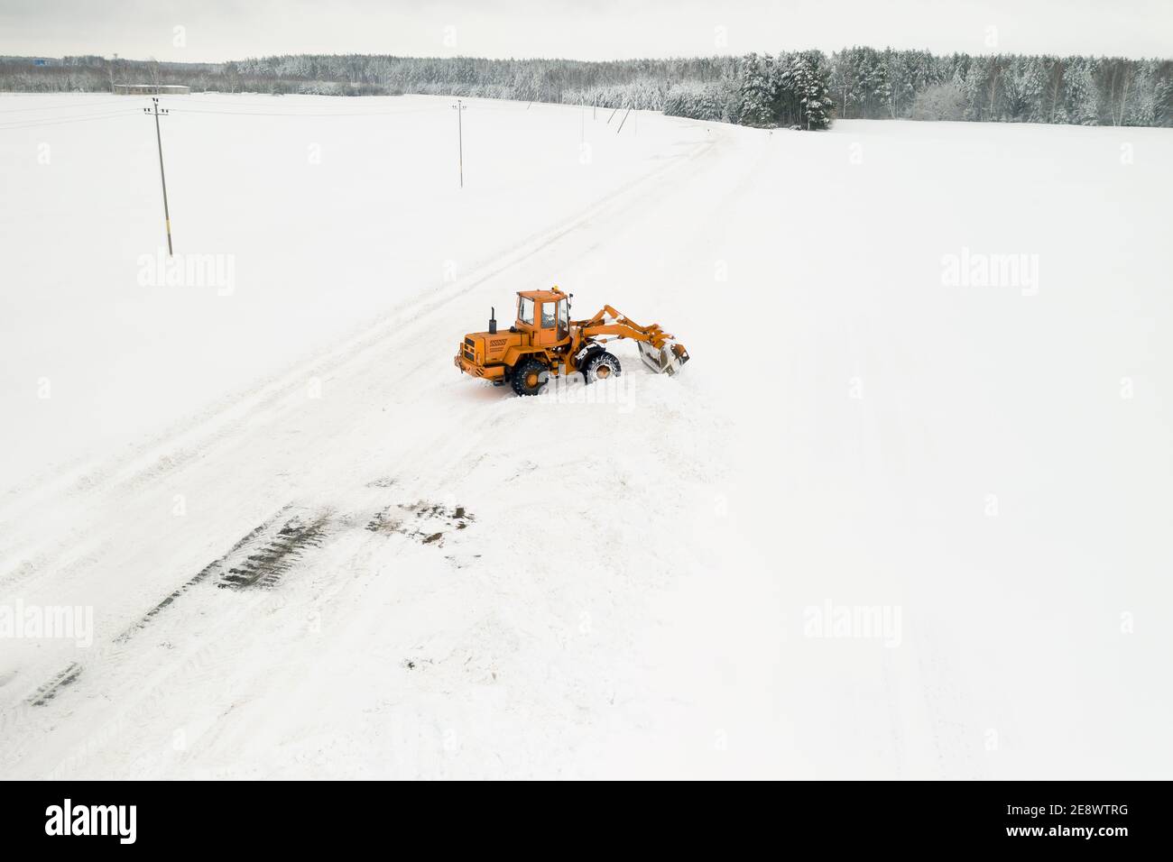 Il trattore giallo con benna rimuove la neve dalla vista dall'alto. Foto Stock