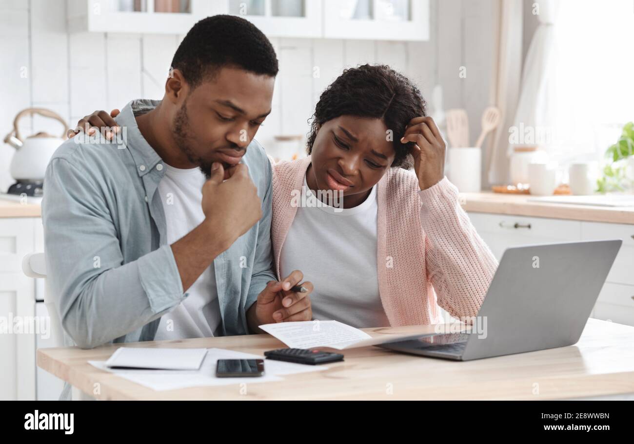 Sottolineato Coppia Nera calcolo bilancio famiglia in cucina, sofferenza crisi finanziaria Foto Stock