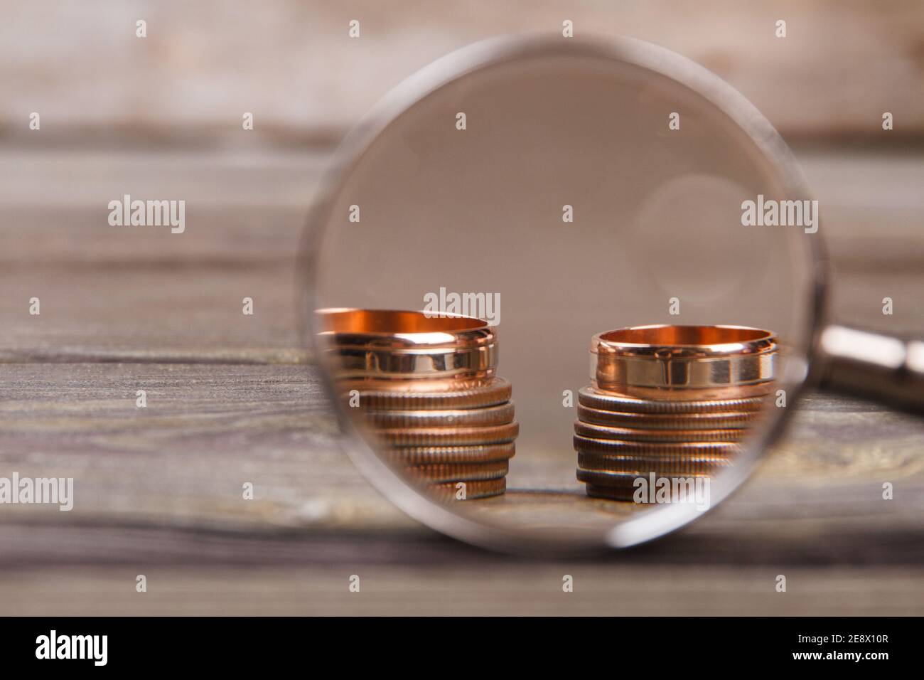 Lente di ingrandimento in vetro e pile di monete. Foto Stock