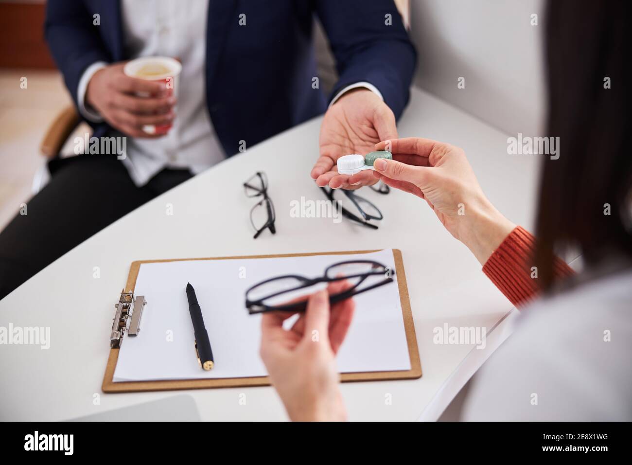 Ottico che offre lenti correttive e un paio di occhiali Foto Stock