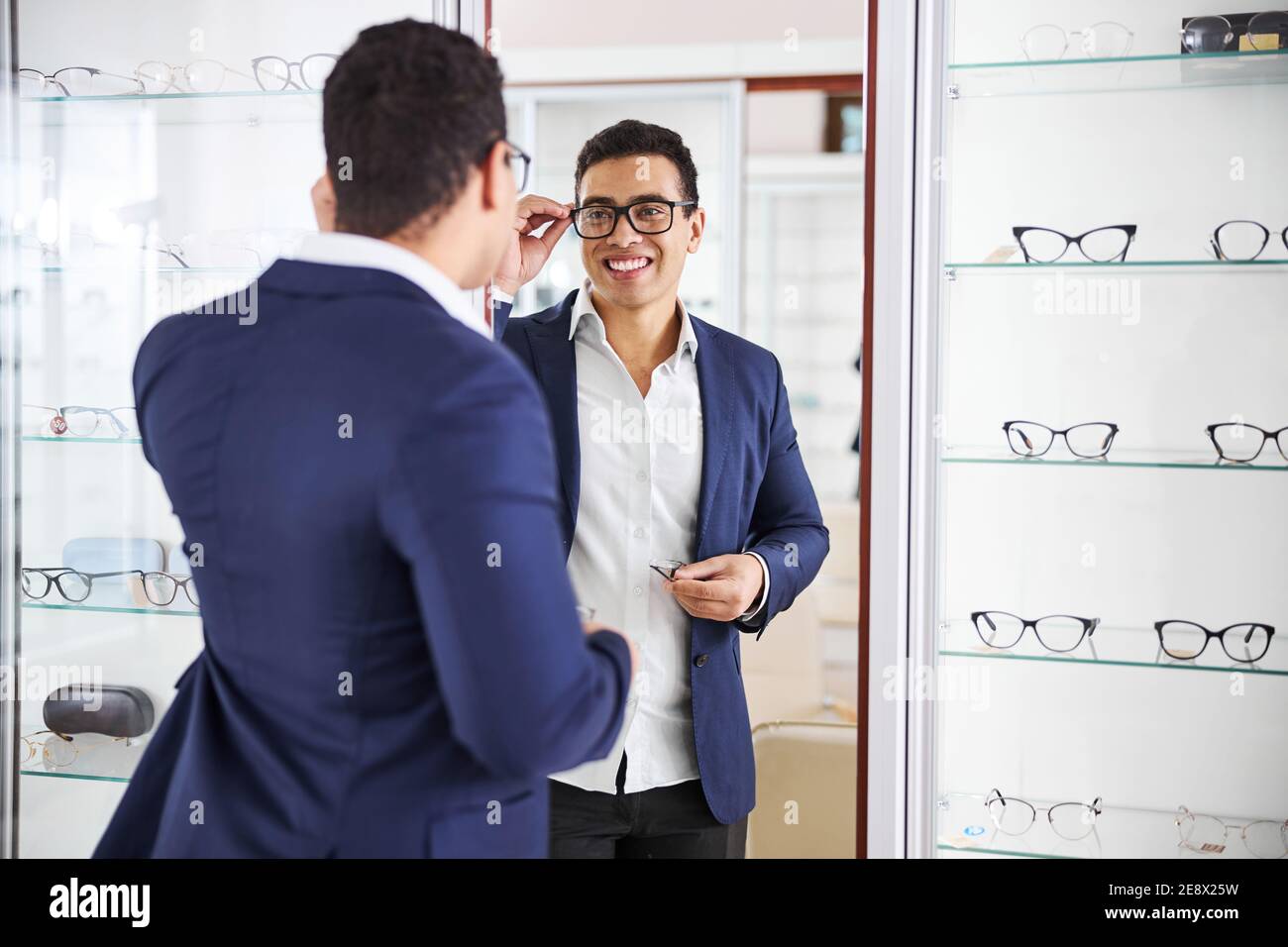 Uomo sorridente che prova su un nuovo paio di occhiali Foto Stock