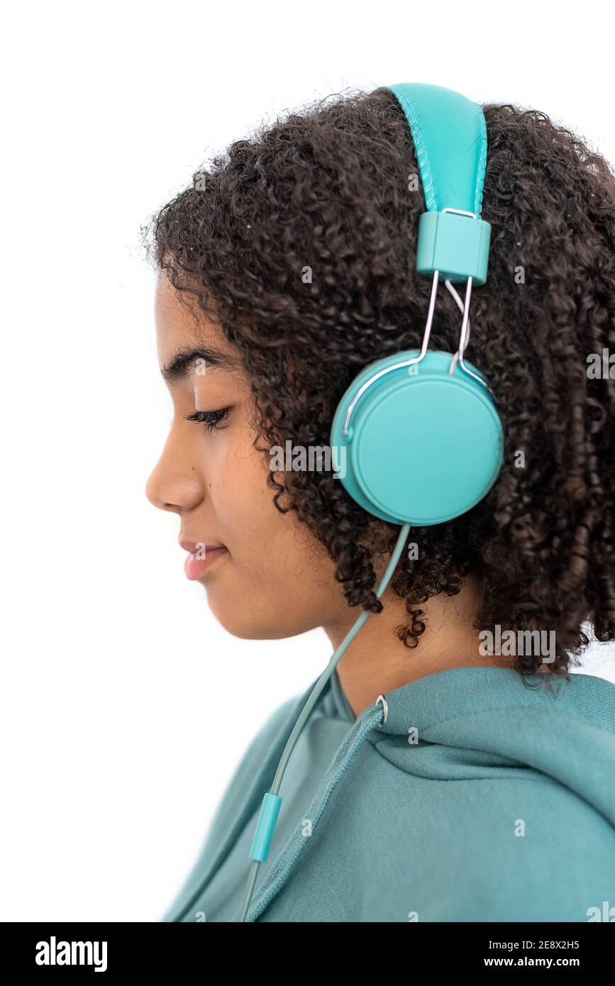 Teenager afroamericano con capelli ricci che guardano verso il basso e ascoltano alla musica con le moderne cuffie turchesi Foto Stock