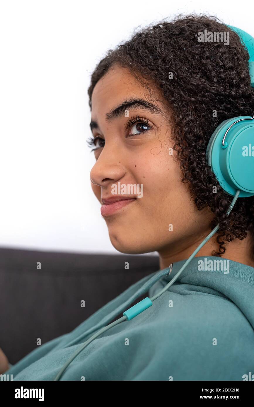 Teenager afroamericano con capelli ricci che ascolta la musica moderne cuffie turchesi Foto Stock