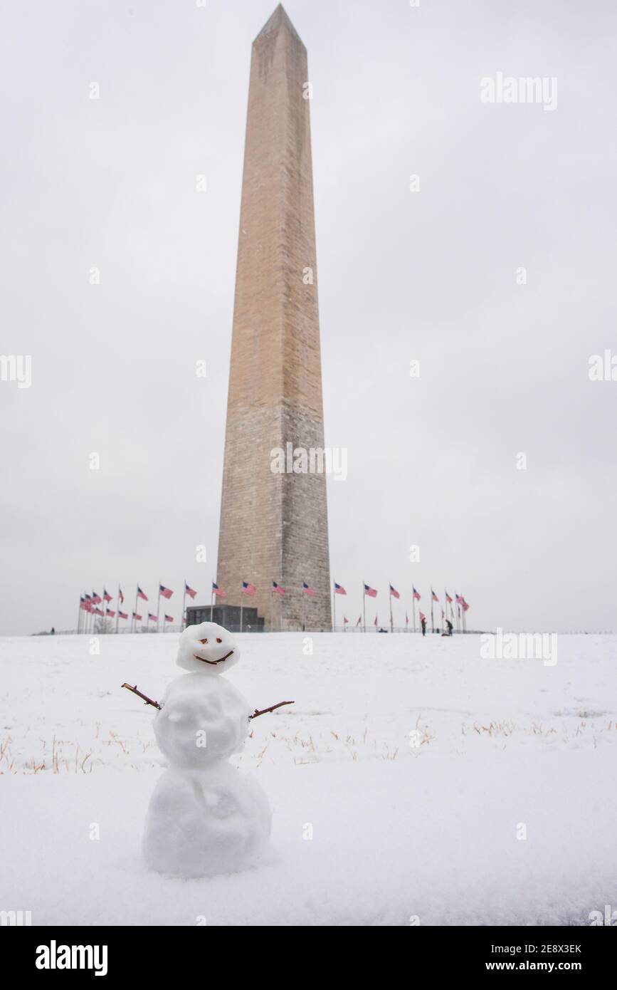 Un simpatico pupazzo di neve sorride ai visitatori di fronte al Washington Monument durante una giornata invernale innevata a Washington, D.C. Foto Stock