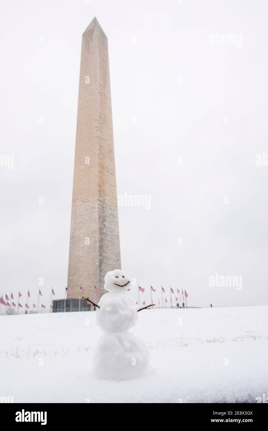 Un simpatico pupazzo di neve sorride ai visitatori di fronte al Washington Monument durante una giornata invernale innevata a Washington, D.C. Foto Stock