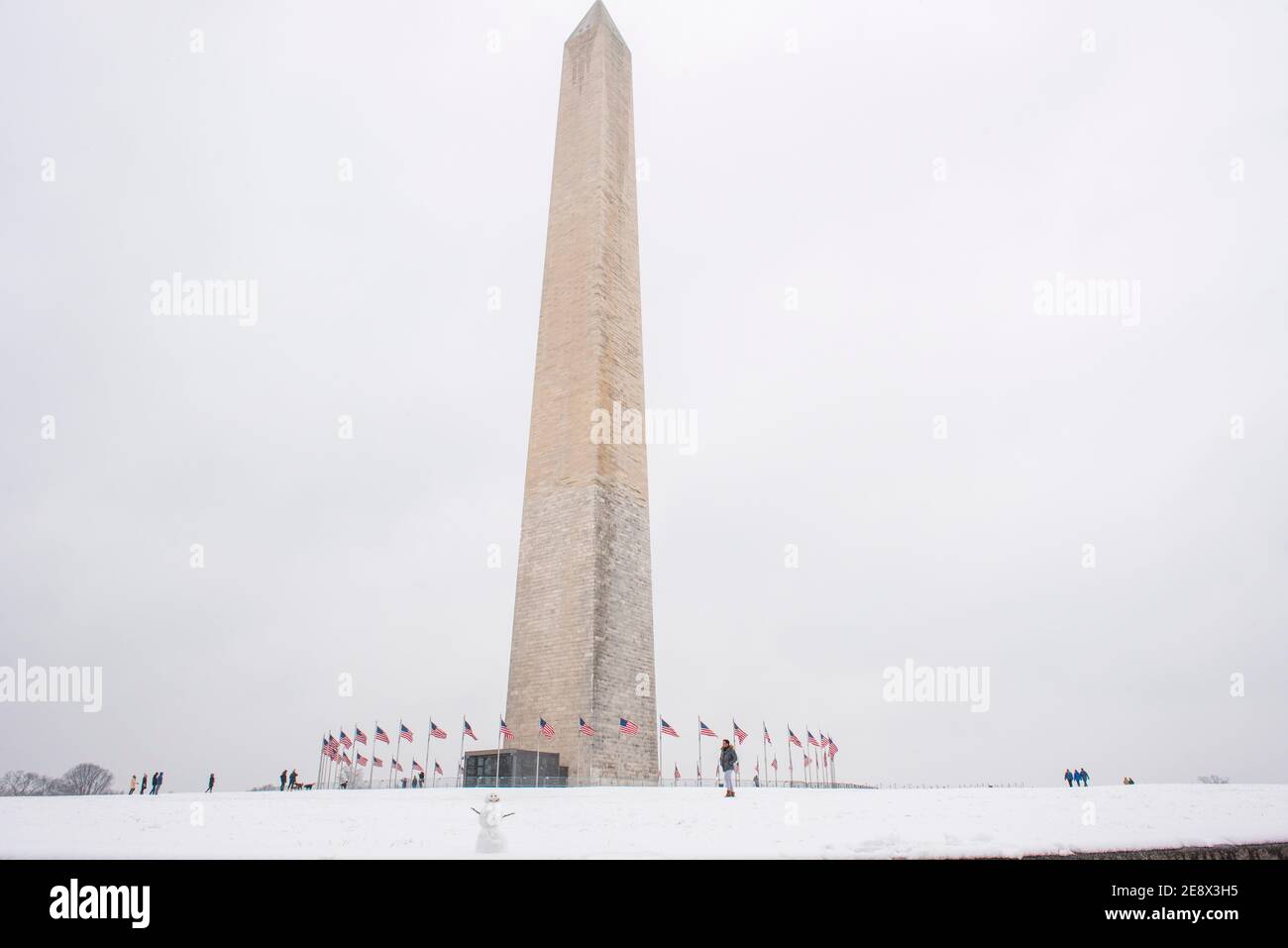 Un simpatico pupazzo di neve sorride ai visitatori di fronte al Washington Monument durante una giornata invernale innevata a Washington, D.C. Foto Stock