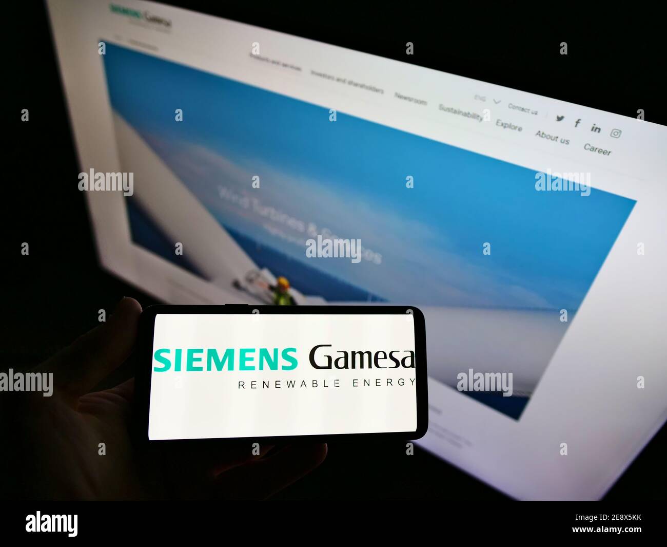 Persona titolare cellulare con logo della società di ingegneria eolica Siemens Gamesa Renewable Energy S.A. in esposizione con sito web. Mettere a fuoco lo schermo del telefono. Foto Stock