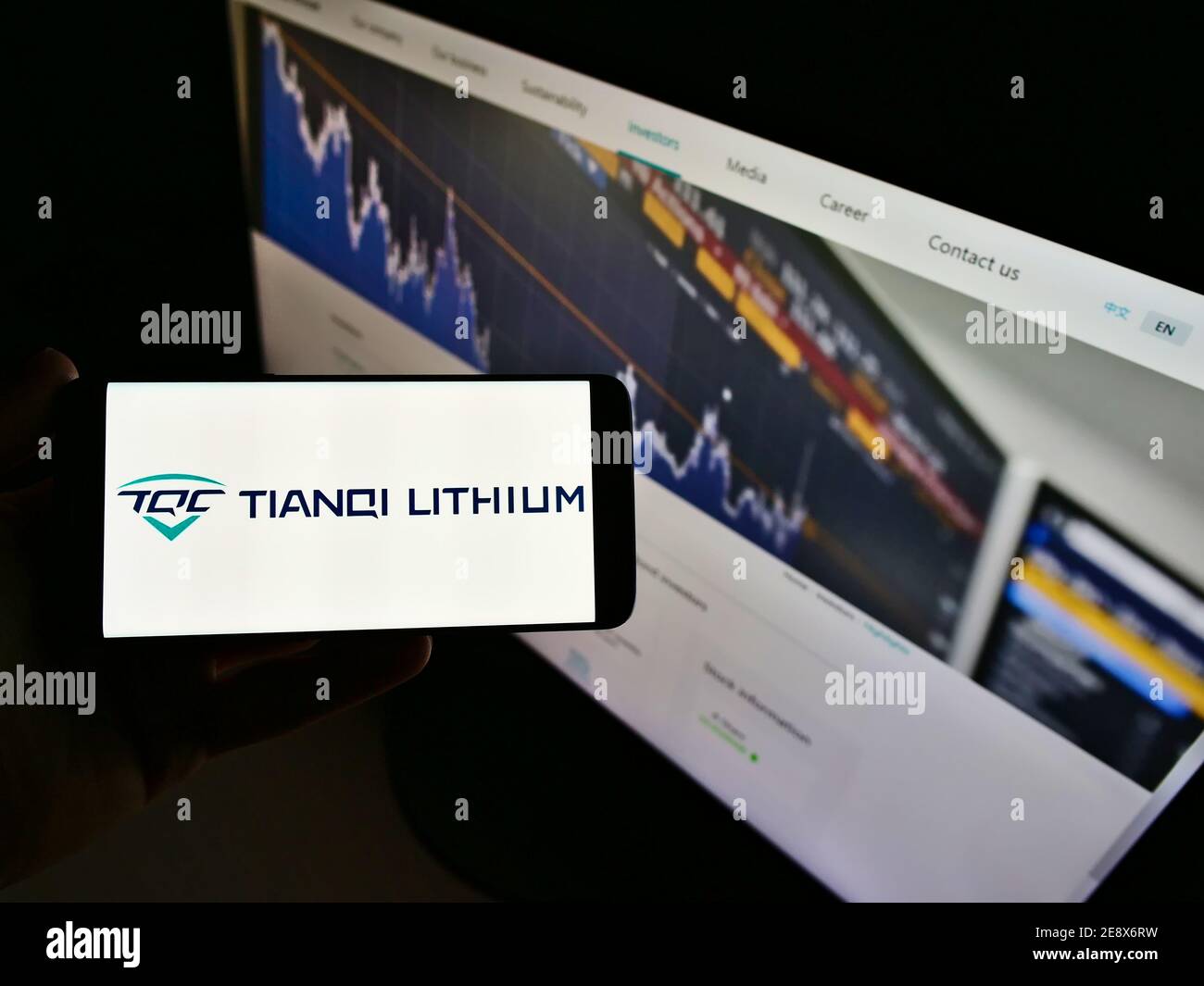 Persona che tiene il cellulare con il logo della società mineraria cinese Tianqi Lithium Corp in esposizione davanti alla pagina web. Mettere a fuoco lo schermo dello smartphone. Foto Stock