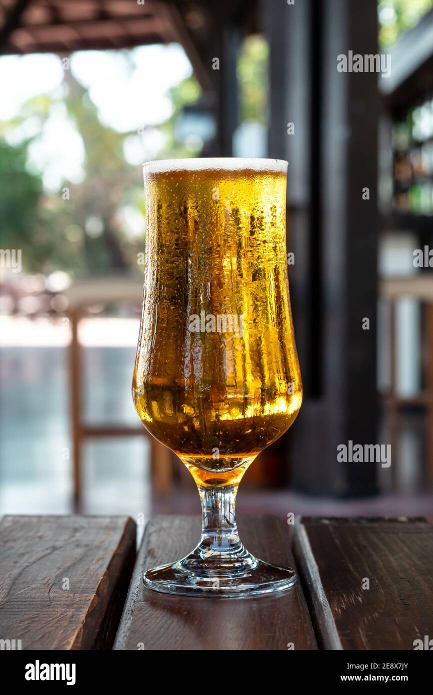 Un bicchiere di birra fredda color ambra con condensa su un tavolo di legno in un pub, bar. Bevanda alcolica. Concetto di svago estivo Foto Stock