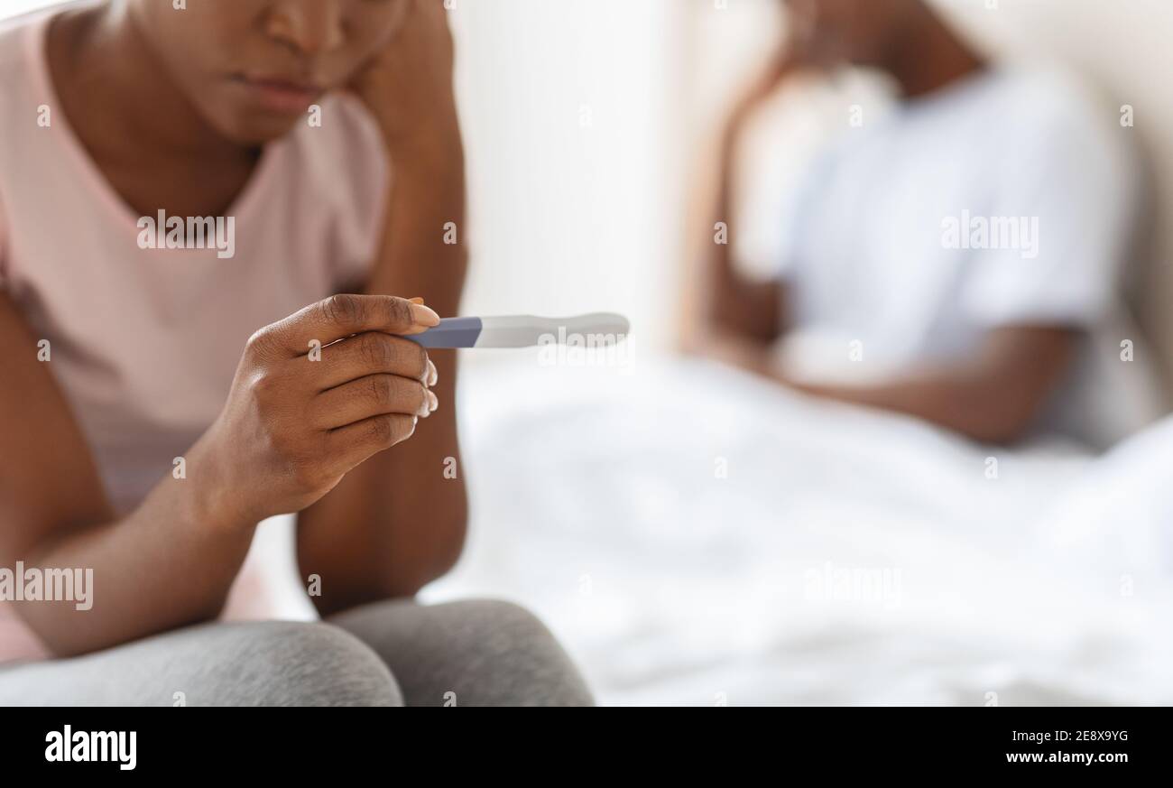 Donna nera irriconoscibile che tiene il test di gravidanza, concetto di gravidanza non intenzionale Foto Stock