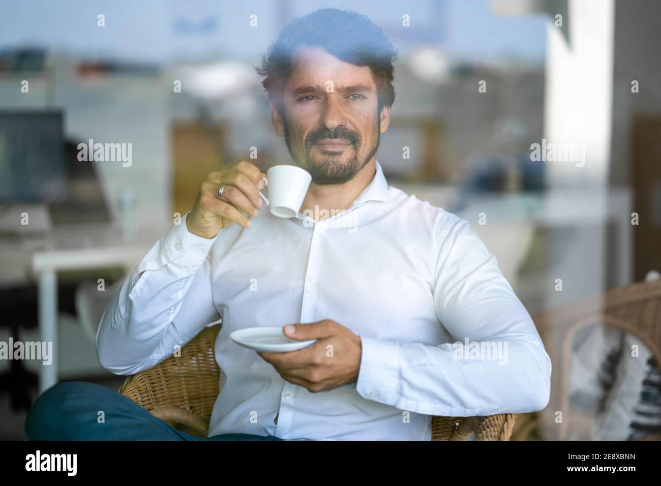 Uomo d'affari informale che indossa bicchieri seduti a bere caffè. Ritratto maschile riuscito con atteggiamento serio e determinato Foto Stock