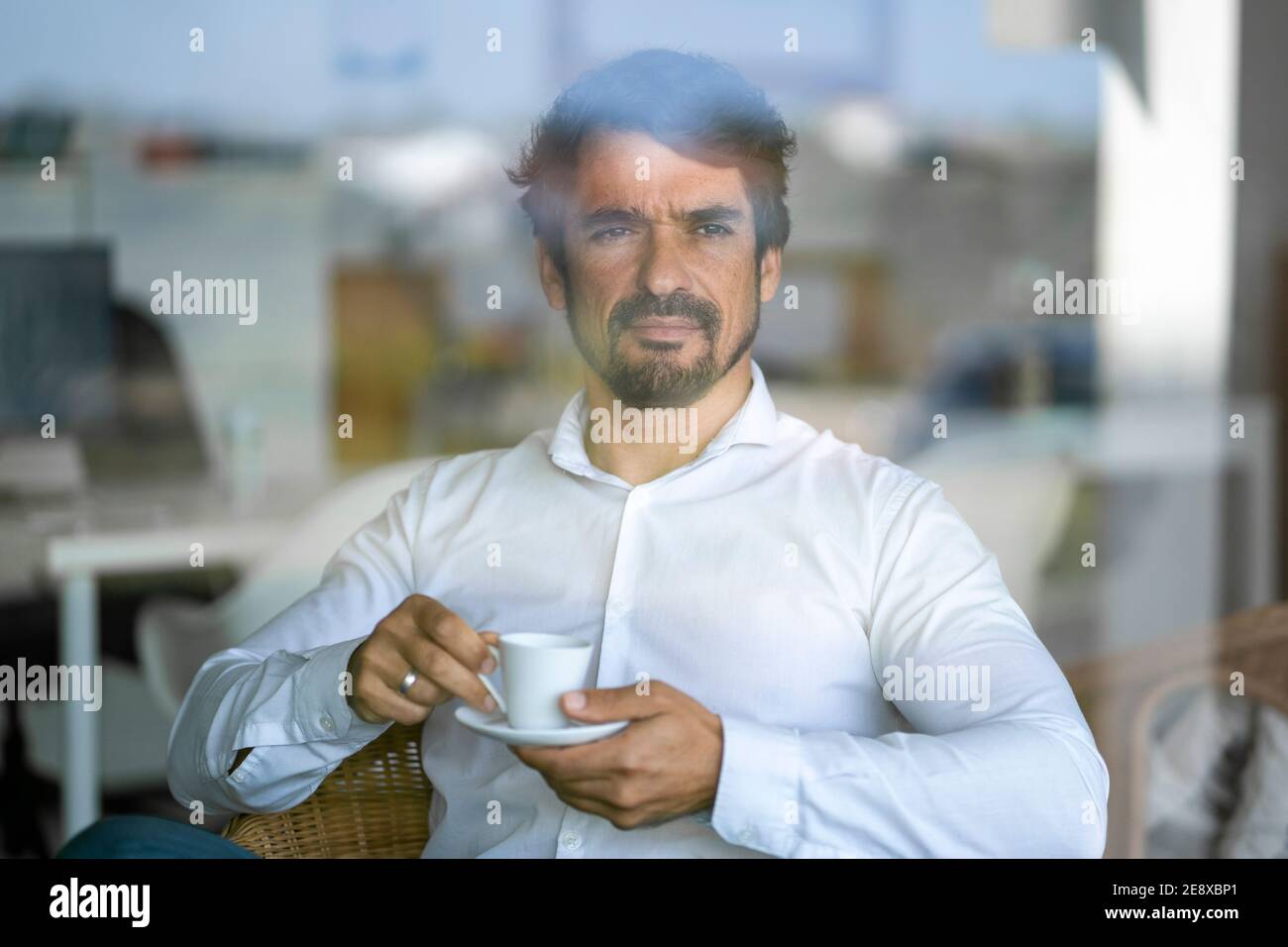 Uomo casual che indossa bicchieri seduti a bere caffè. Ritratto maschile riuscito con atteggiamento serio e determinato Foto Stock