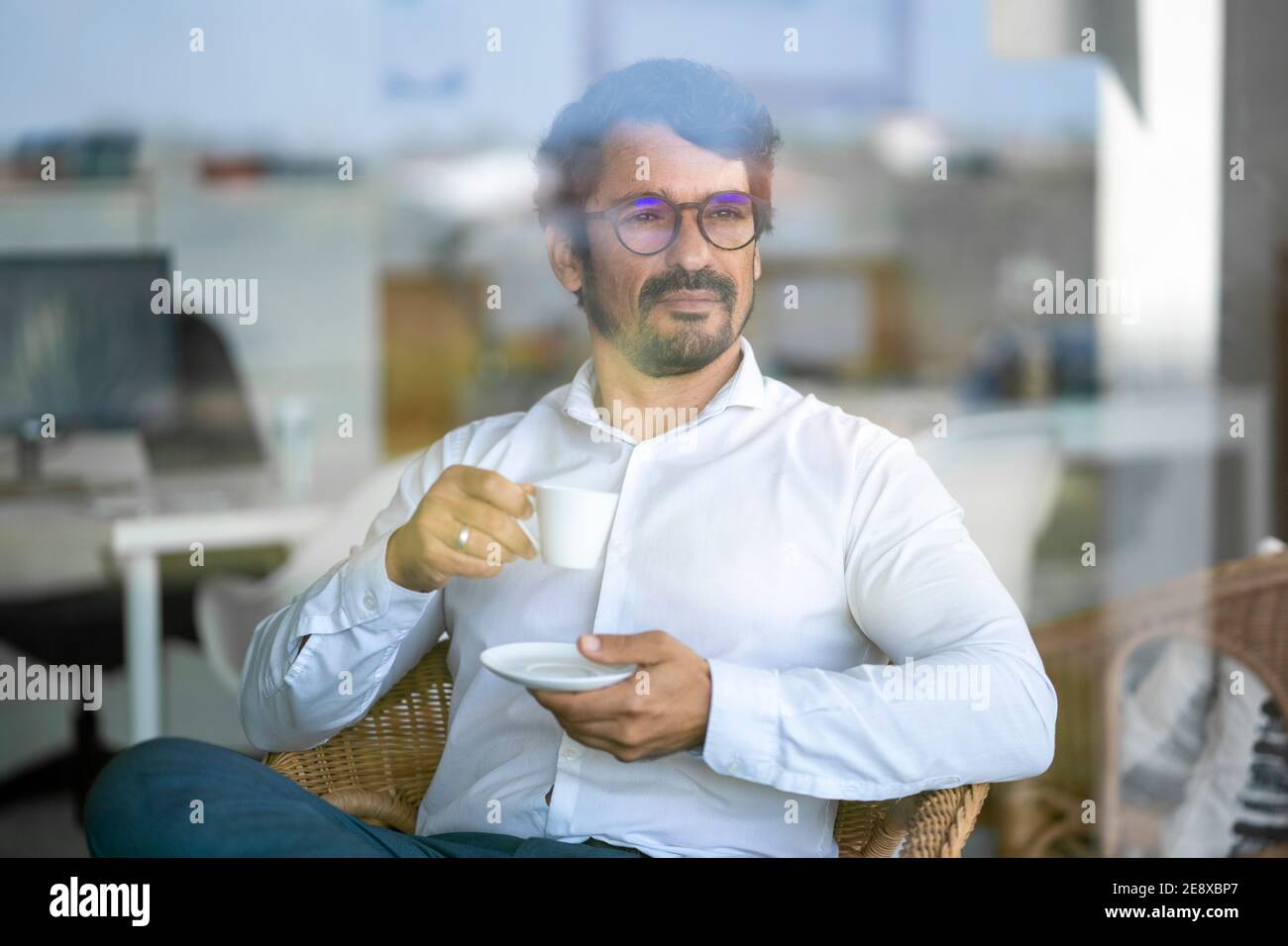 Uomo d'affari informale che indossa bicchieri seduti a bere caffè. Ritratto maschile riuscito con atteggiamento serio e determinato Foto Stock