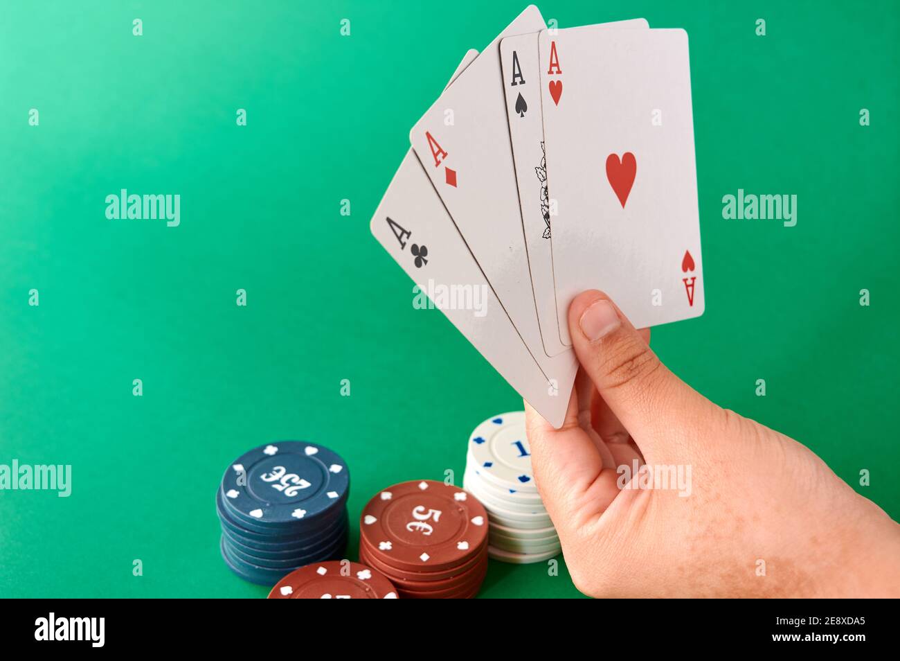 Pila di chip e mano con quattro assi, stoffa di Poker, un mazzo di carte, mano di poker e chip. Sfondo. Foto Stock