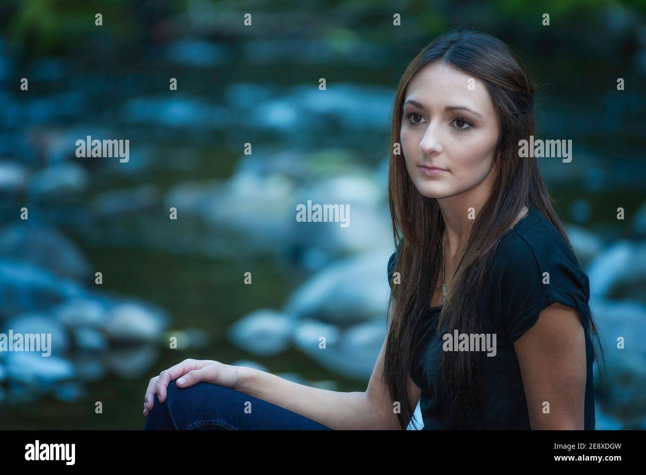 Una giovane donna si pone lungo le rive di un piccolo fiume. Foto Stock