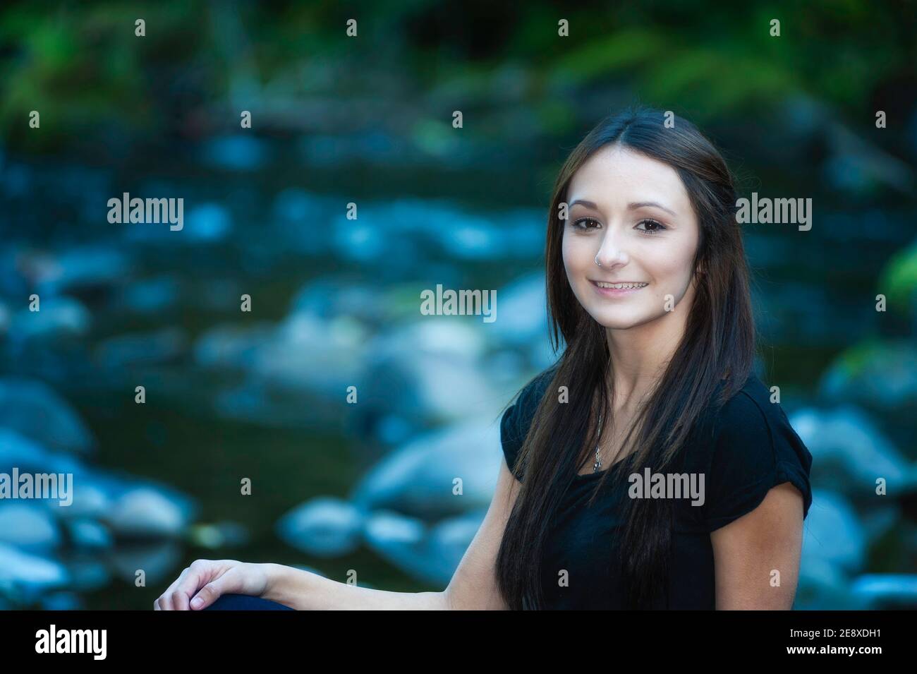 Una giovane donna si pone lungo le rive di un piccolo fiume. Foto Stock