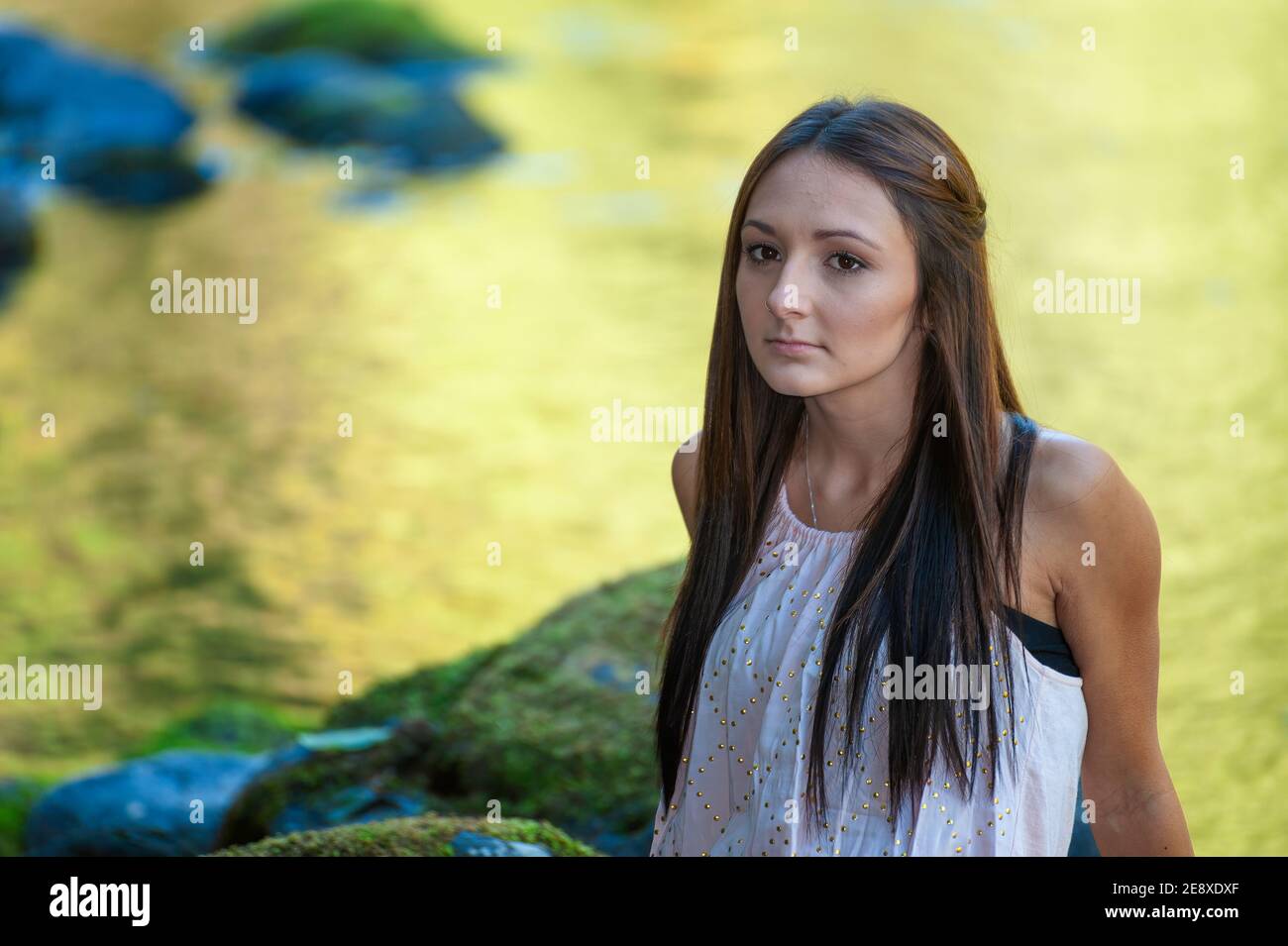 Una giovane donna si pone lungo le rive di un piccolo fiume. Foto Stock