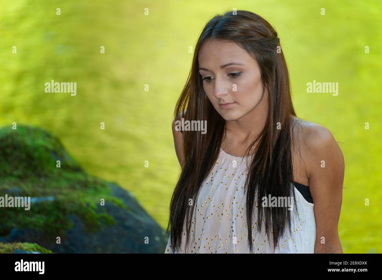 Una giovane donna si pone lungo le rive di un piccolo fiume. Foto Stock