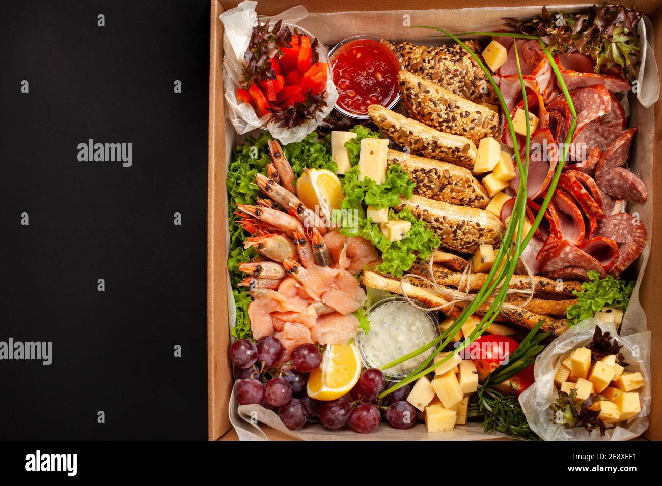 Una scatola di cibo, formaggio, pane, pesce, gamberetti. Consegna di cibo  per l'azienda, cena romantica, cena in ufficio a casa. Bella composizione  di cibo in un Foto stock - Alamy