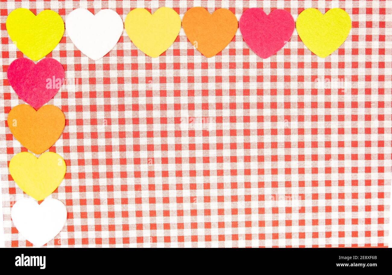 Con uno sfondo rosso e bianco tessuto Vichy per il giorno di San Valentino con rosa, arancione, giallo e bianco cuori. Il giorno di San Valentino del concetto. Foto Stock