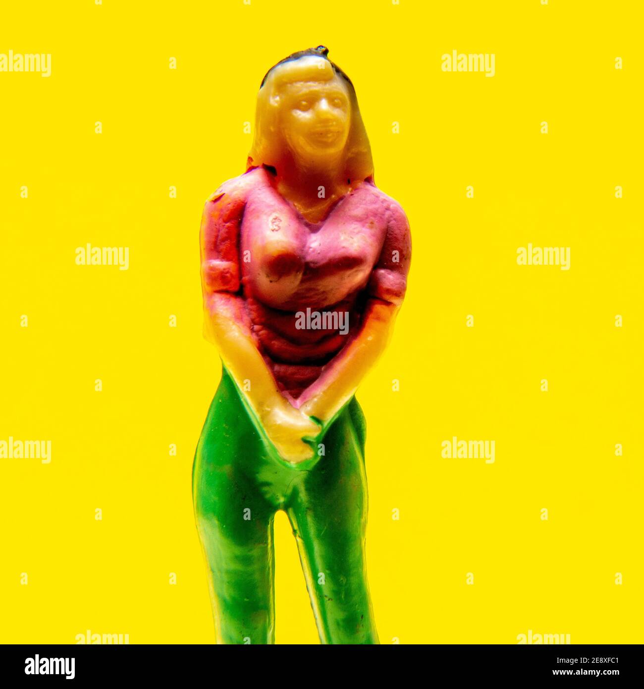 La statuetta colorata si staglia su uno sfondo giallo brillante, mostrando un design vivace e un'estetica giocosa Foto Stock