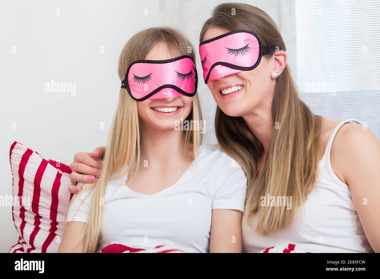 Madre e figlia che indossano le maschere per dormire a letto Foto Stock