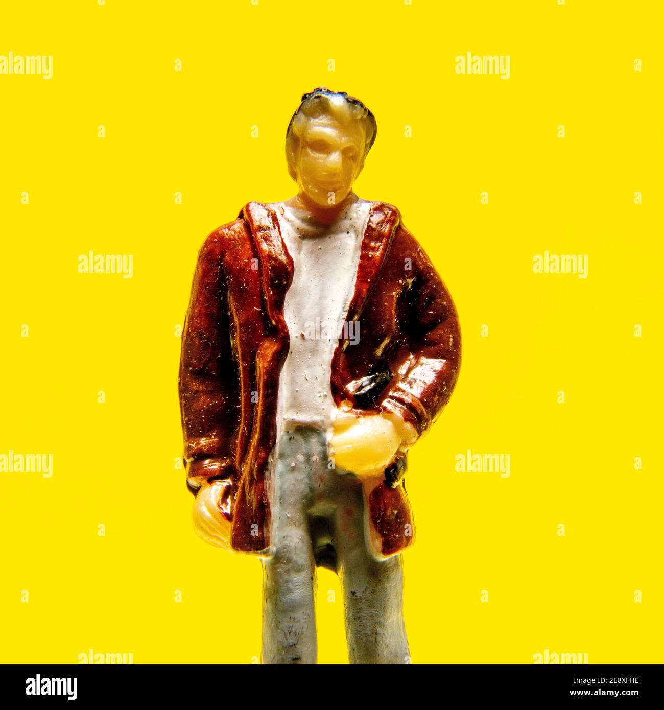 Statuetta in piedi su uno sfondo giallo brillante, che mostra dettagli e abbigliamento casual in una presentazione artistica unica Foto Stock