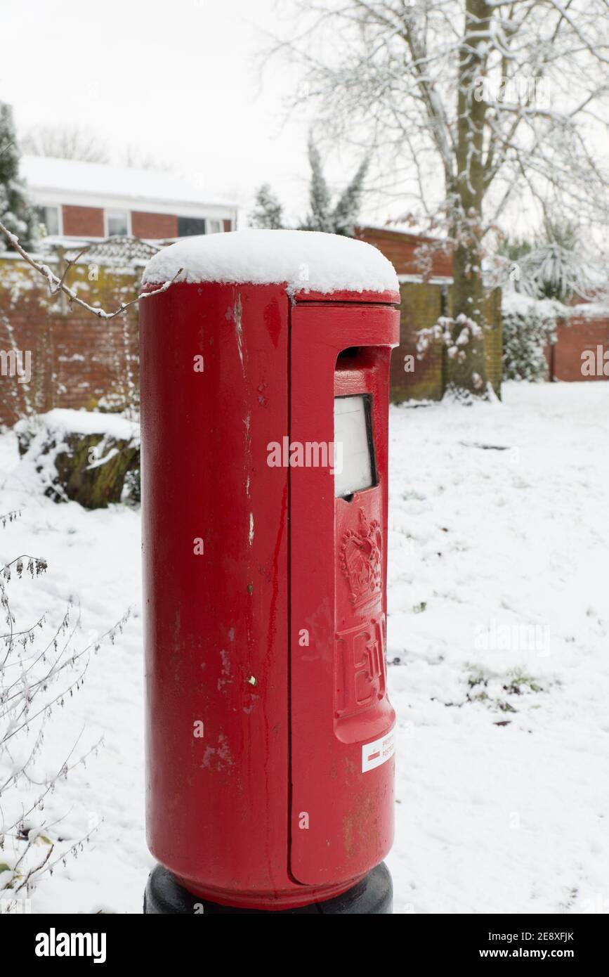 Primo piano di casella di posta reale britannica brillante a strada coperta di neve in una fredda giornata invernale Foto Stock