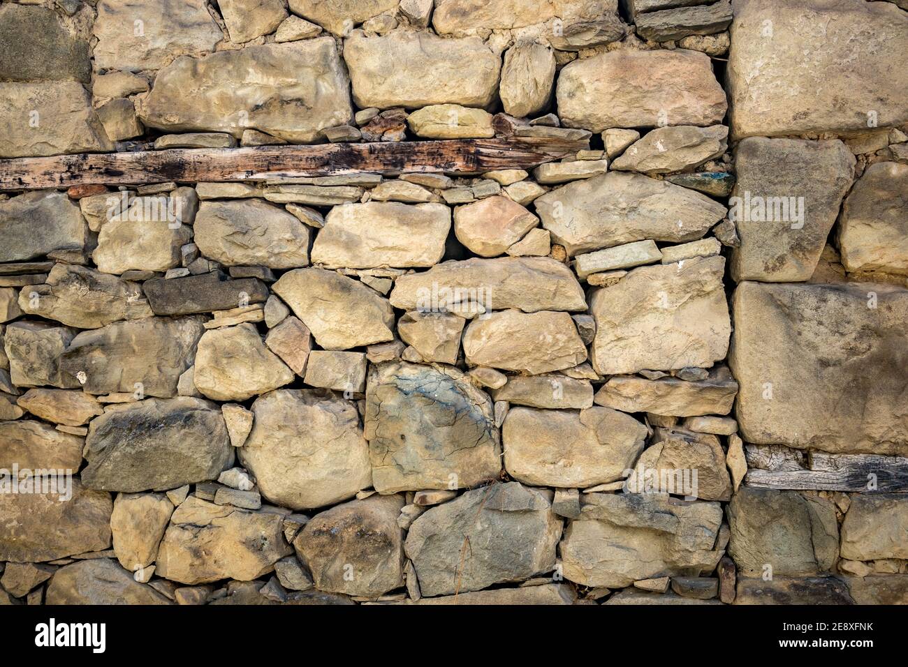 Vecchio muro di pietra, costruzione asciutta. Spring Street vista parziale, città di Metsovo, Epiro, Grecia. La struttura è popolare stazione sciistica invernale greca con vecchie case in stile balcanico. Sfondo, sfondo Foto Stock