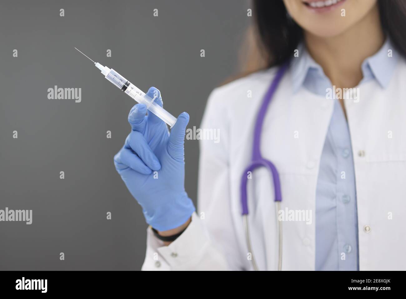 Medico in guanti di gomma che tengono una siringa con un closeup del medicinale Foto Stock