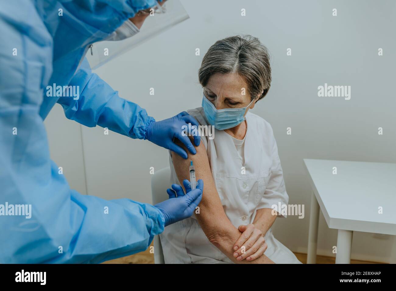 Medico in tuta protettiva e guanti per la vaccinazione COVID-19 Foto Stock