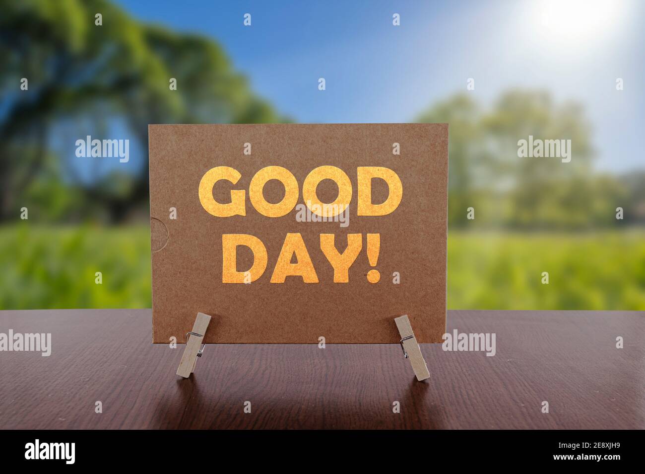 Buon giorno testo sulla carta sul tavolo con sfondo verde soleggiato parco. Foto Stock