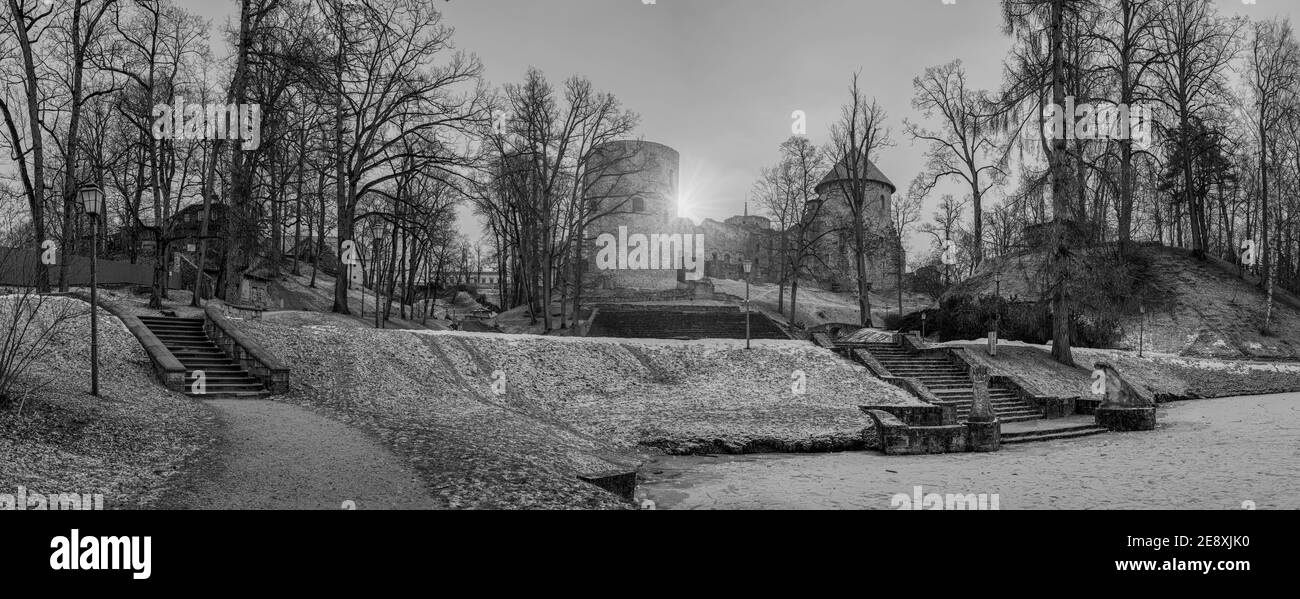 Immagine panoramica in bianco e nero delle rovine del castello medievale di Cesis in un bellissimo parco con lago ghiacciato e scale di pietra a Cesis, Lettonia Foto Stock