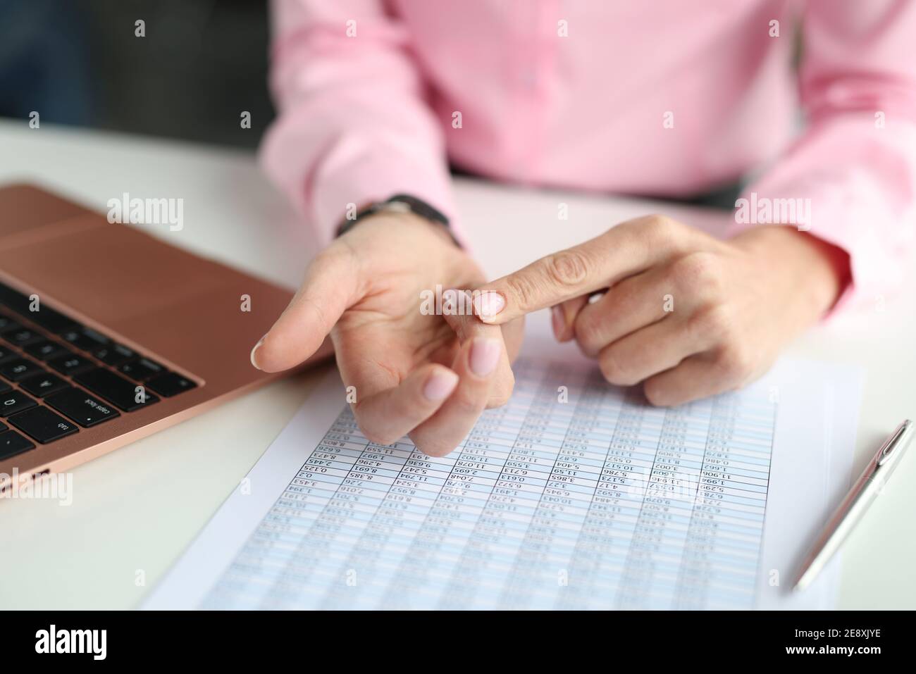 Donna che si arriccia le dita sul tavolo con numeri e computer portatile primo piano Foto Stock