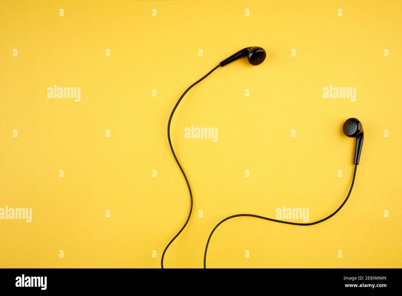 auricolari neri isolati su uno sfondo giallo caldo alla moda. stile di vita musicale. spazio per la copia. disposizione piatta Foto Stock