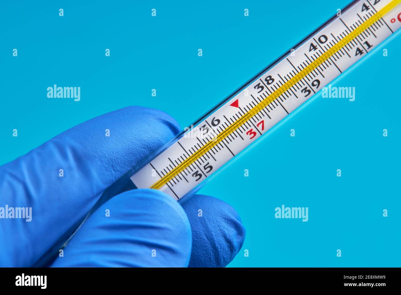 la persona in guanti medici contiene termometro al mercurio che mostra 37 temperatura. concetto di febbre Foto Stock
