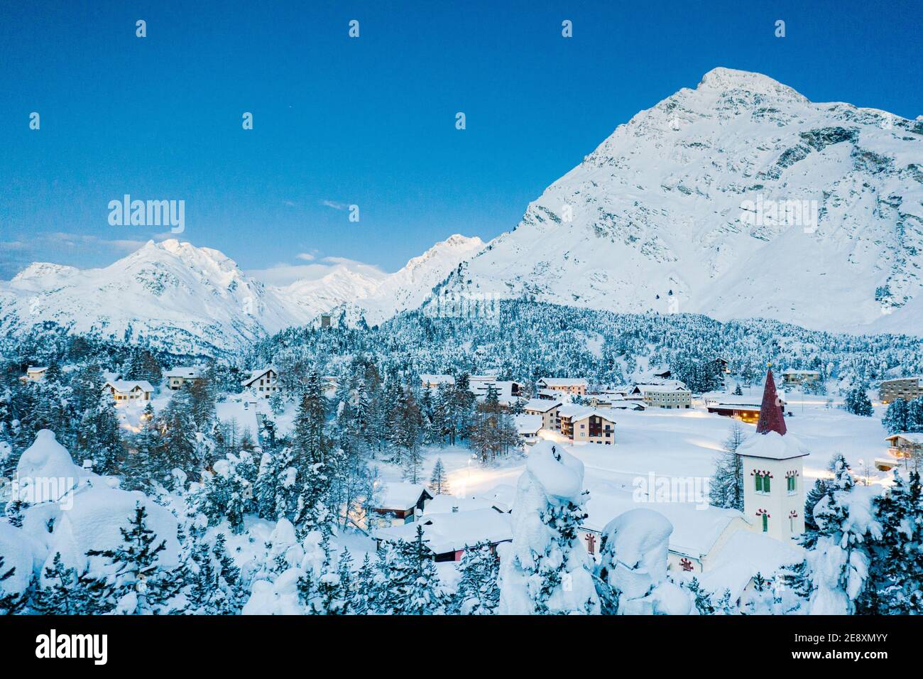 Montagne innevate e Chiesa Bianca al tramonto, Maloja, Bregaglia, cantone di Graubunden, Engadin, Svizzera Foto Stock