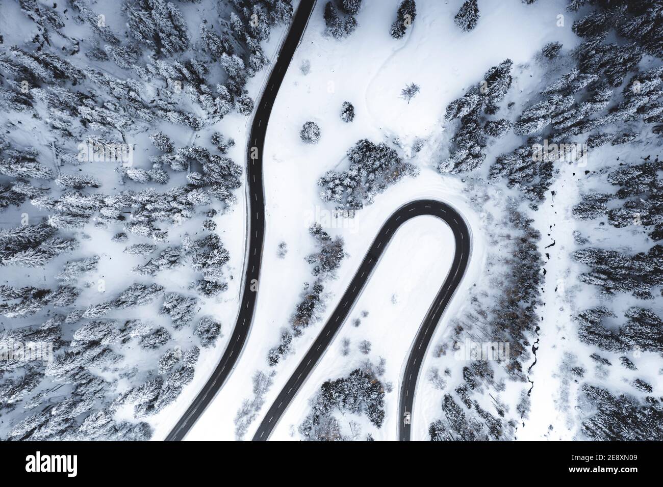 Vista aerea della strada di montagna vuota nei boschi innevati Foto Stock