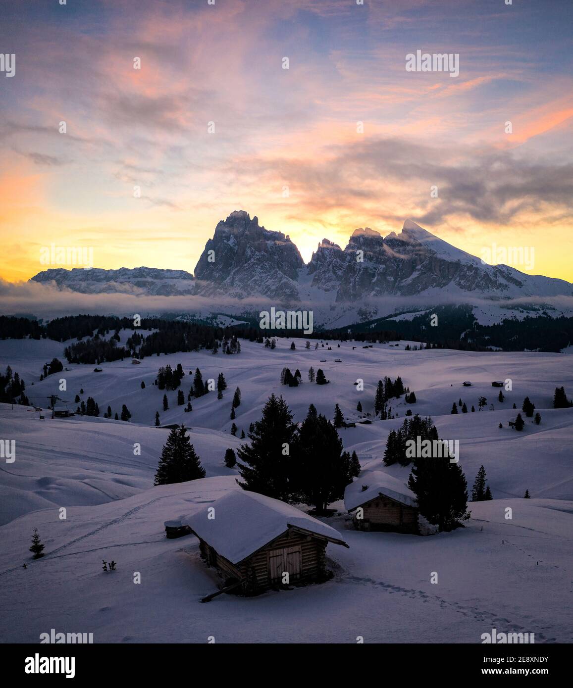 Chalet in legno coperto di neve all'alba con Sassolopiatto e Sassolungo sullo sfondo, Alpe di Siusi, Dolomiti, Alto Adige, Italia Foto Stock