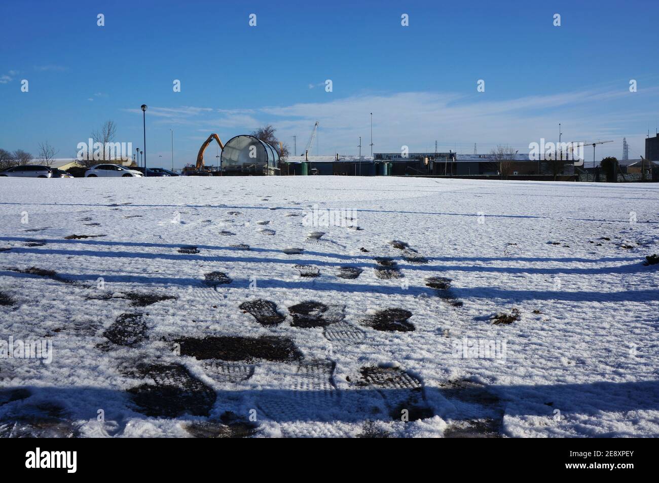 Impronte di piede nella neve in un parcheggio vuoto che conduce all'orizzonte Foto Stock