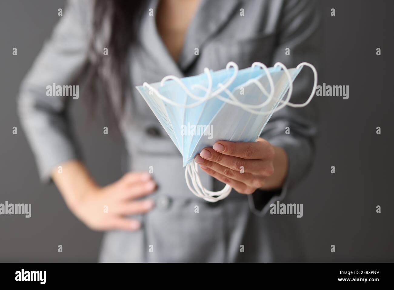 Donna che tiene molte maschere mediche protettive nelle sue mani Foto Stock