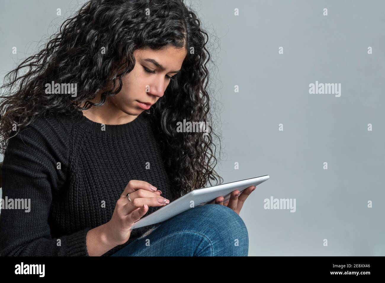 La ragazza nera dai capelli lunghi usa il suo tablet Foto Stock
