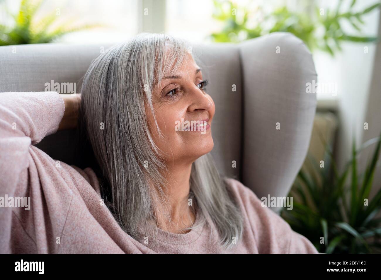 Vista frontale ritratto di donna anziana felice seduto in casa. Foto Stock