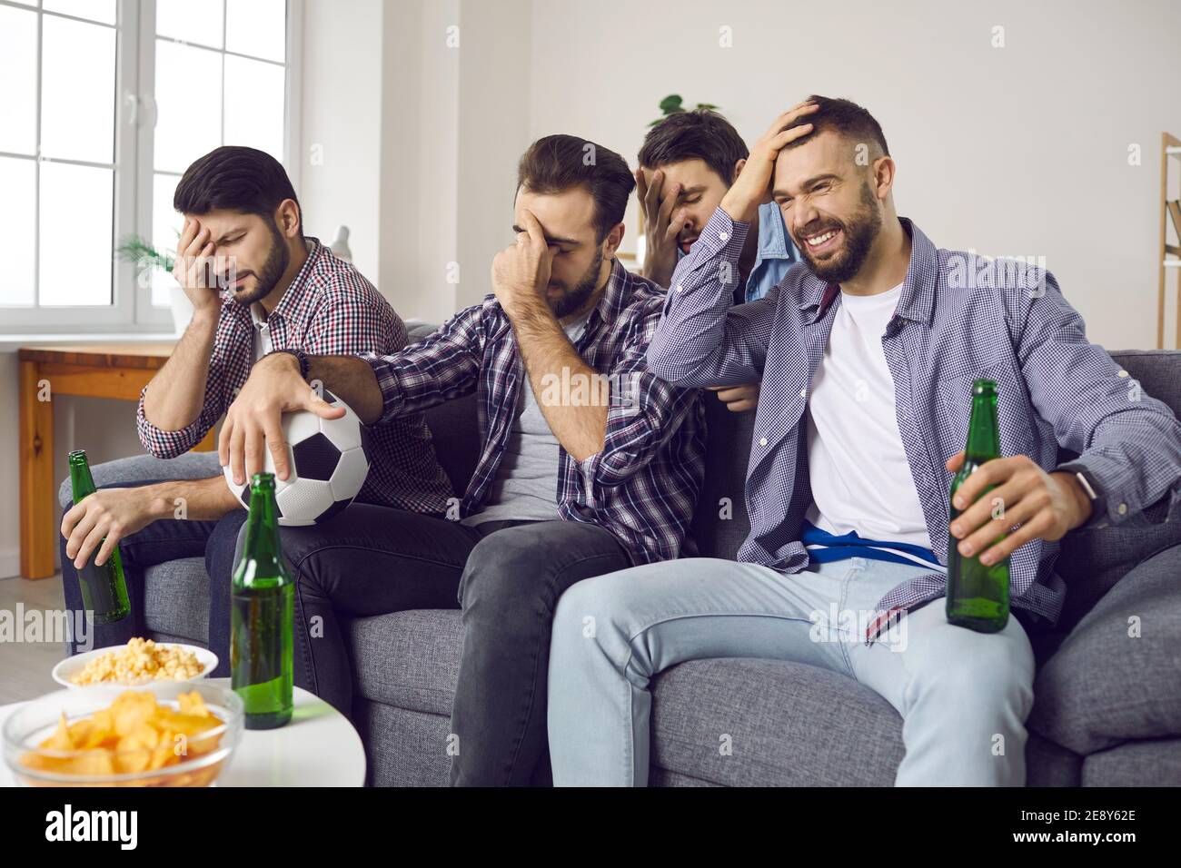 I fan sono rimasti delusi e si sono seduti sul divano di casa e guardati terribili Partita di calcio in TV Foto Stock