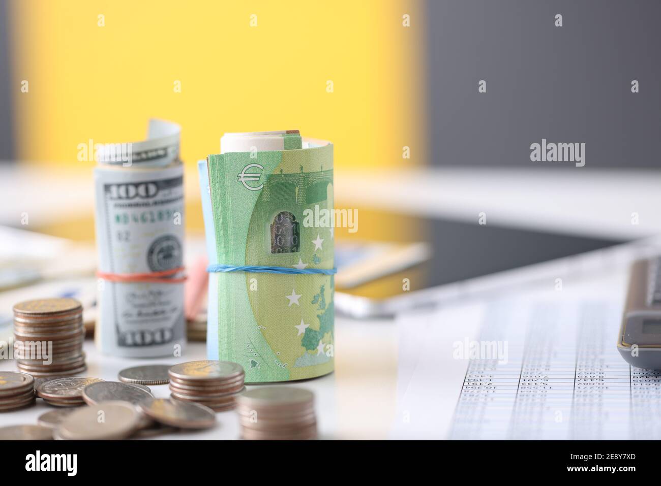 Carta arrotolata in dollari e in euro e monete giacciono sul tavolo primo piano Foto Stock