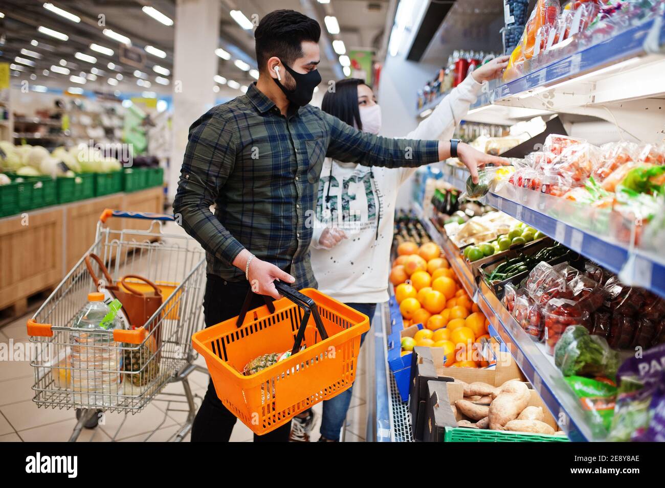 Coppia asiatica indossare in maschera protettiva faccia shopping insieme in supermercato durante pandemia. Prendere le verdure dal frigorifero. Foto Stock