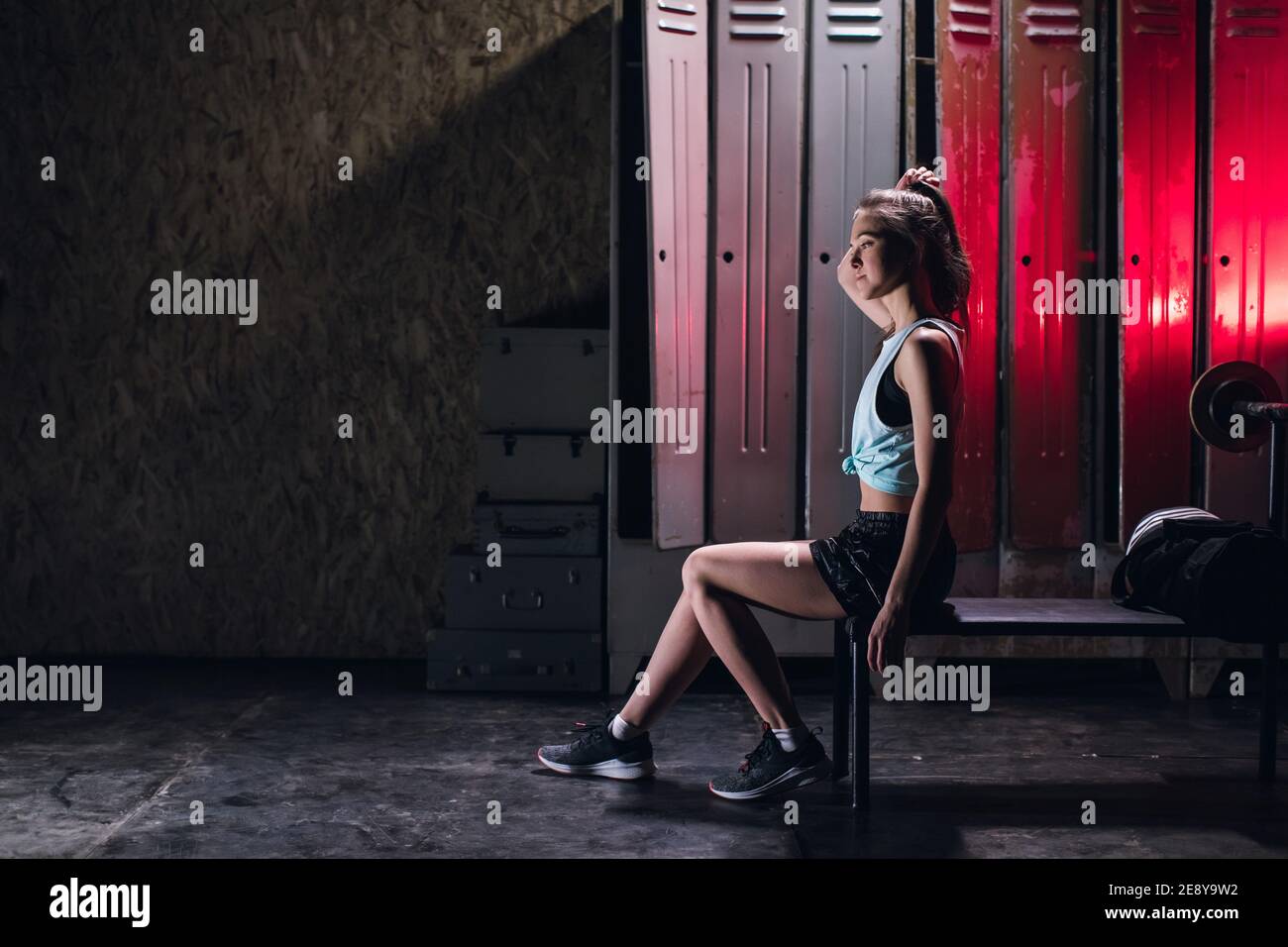 la giovane ragazza si trova in una sala fitness d'atmosfera contro il sfondo di armadietti per spogliatoio Foto Stock